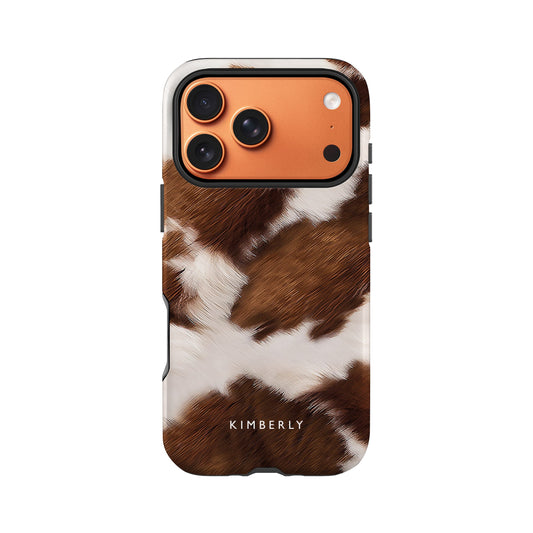 a phone case with a cow pattern, including brown and white fur.